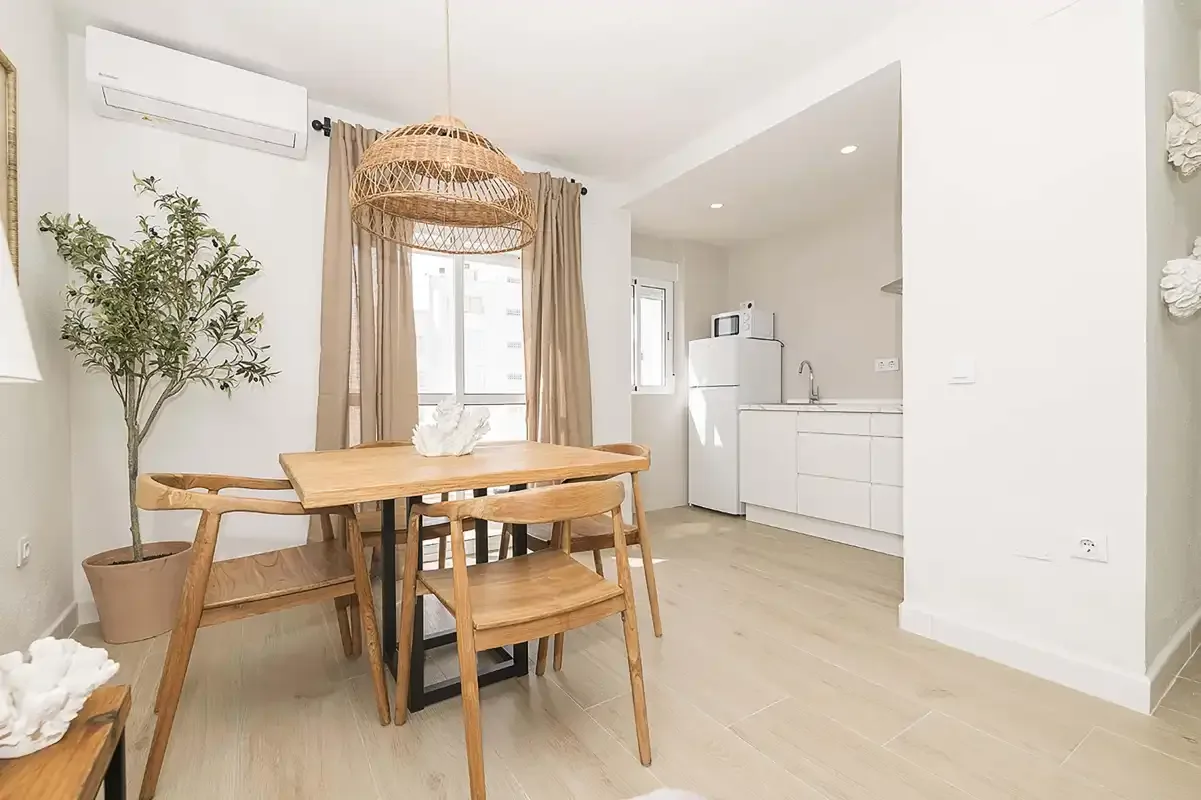Un comedor con una mesa de madera junto a una cocina compacta.