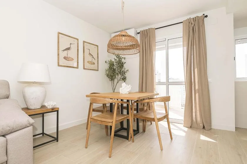 Un comedor con una mesa de madera y sillas junto a una ventana con cortinas.