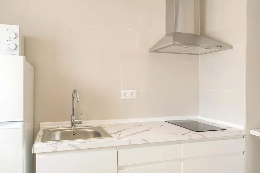Una cocina moderna con fregadero y placa de cocina sobre una encimera clara.