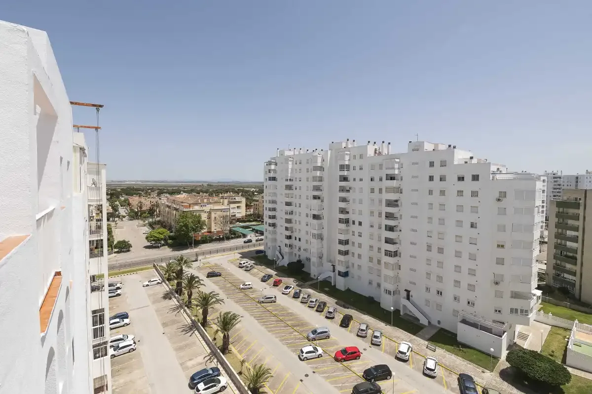 Vista de edificios de apartamentos y una zona de estacionamiento bajo un cielo despejado.