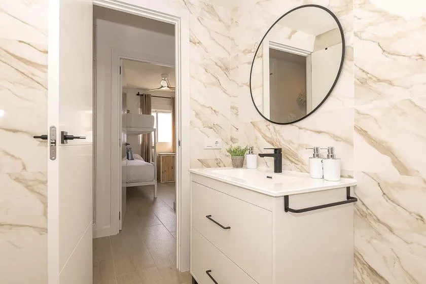 Un lavabo de baño con espejo ovalado junto a una puerta abierta.