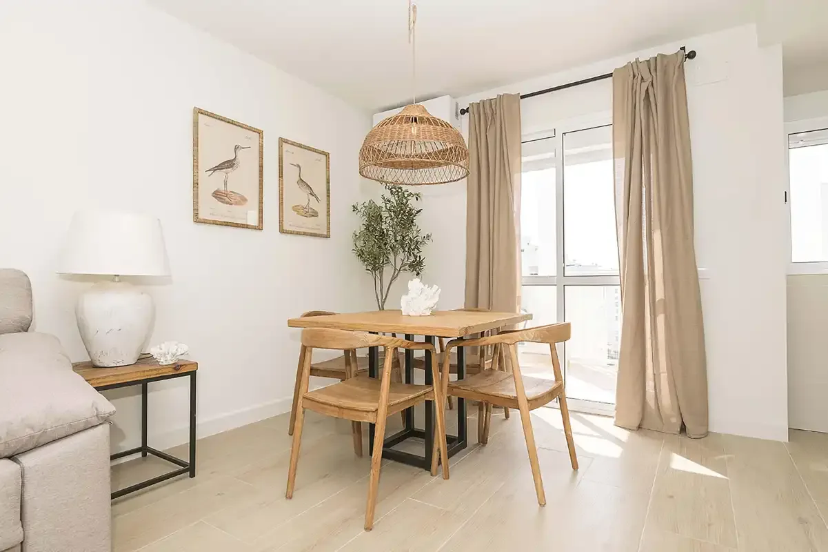 Un comedor luminoso con una mesa de madera, asientos y una ventana grande.