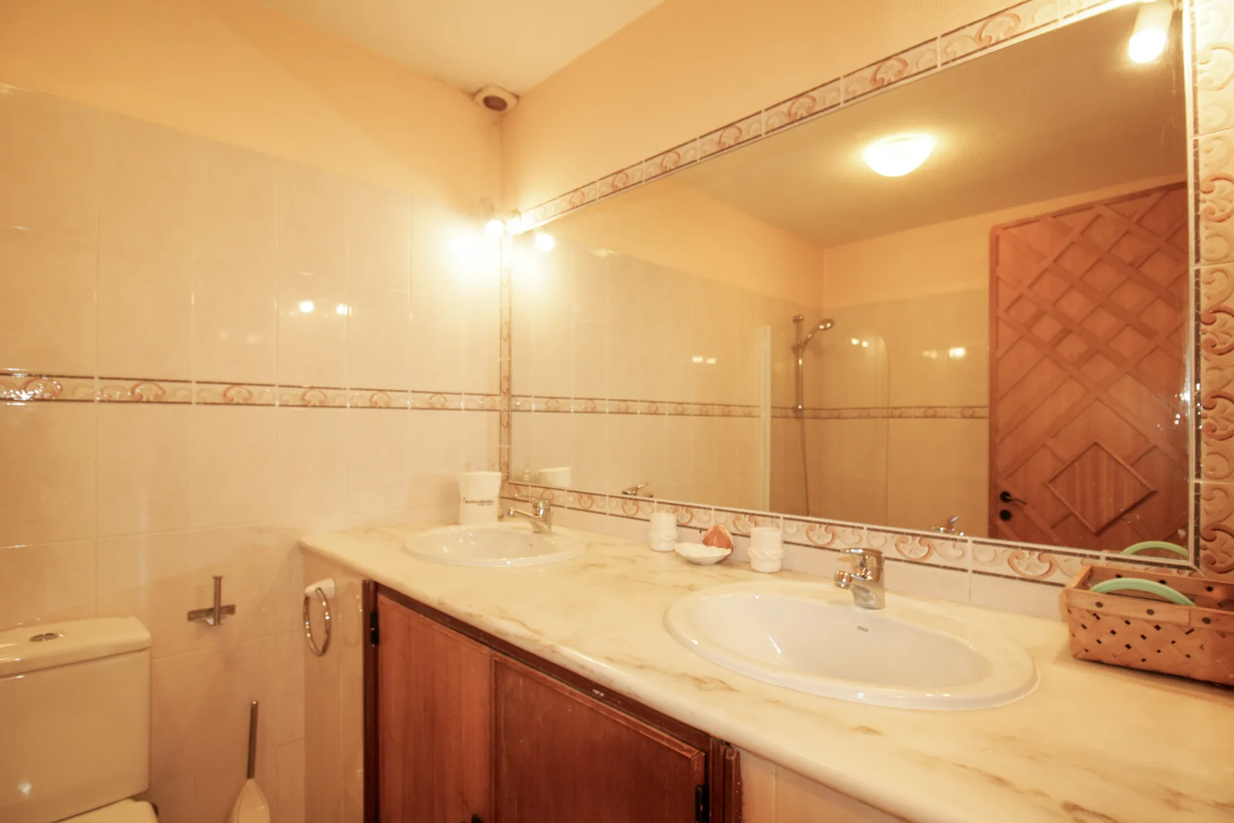 Un tocador de baño alicatado con dos lavabos y un gran espejo.