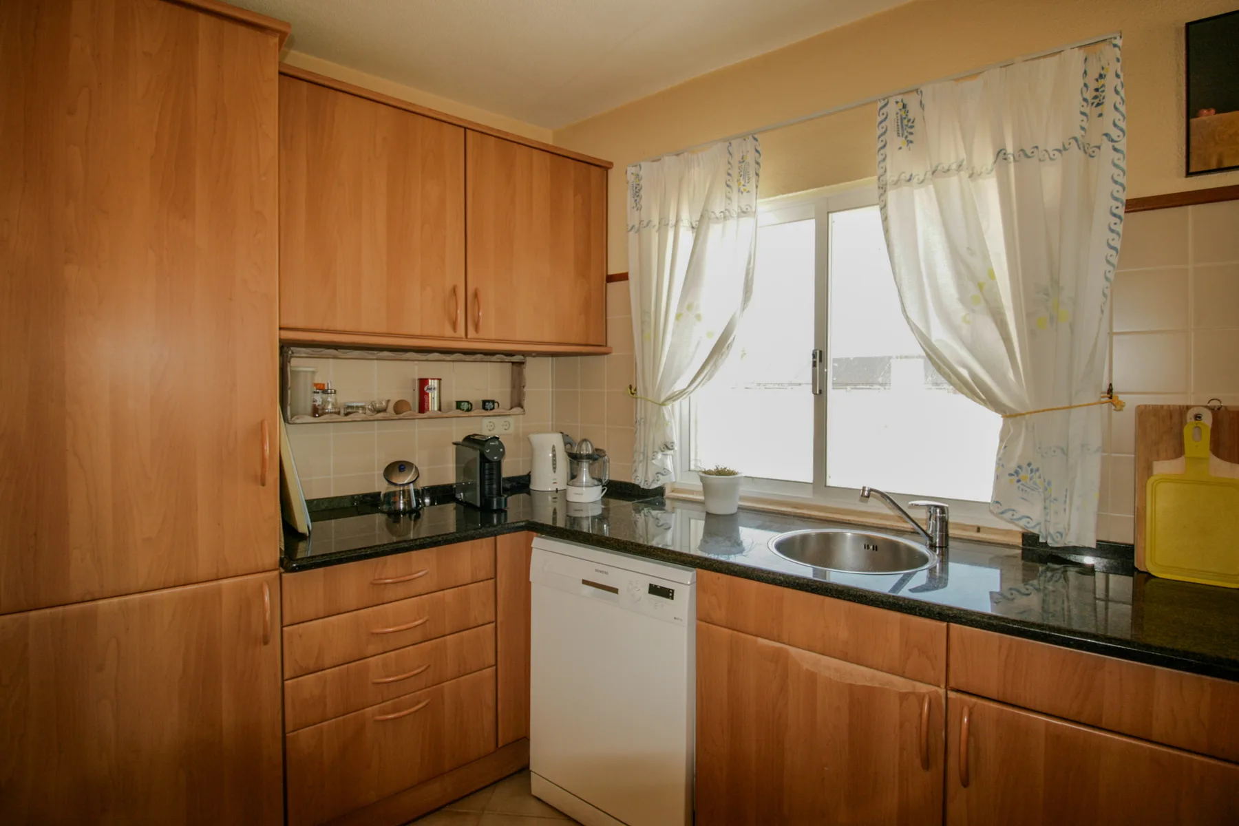 Una cocina con armarios de madera, una encimera y un fregadero junto a una ventana.