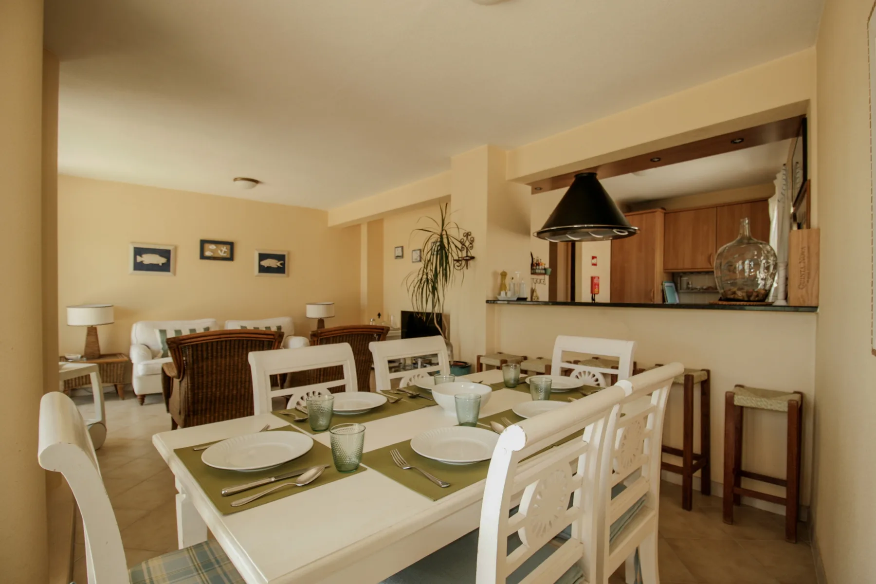 Comedor con la mesa preparada y una cocina abierta al fondo.