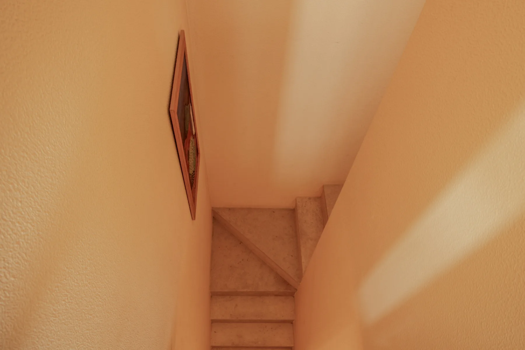 Una escalera interior estrecha con una obra enmarcada en la pared.