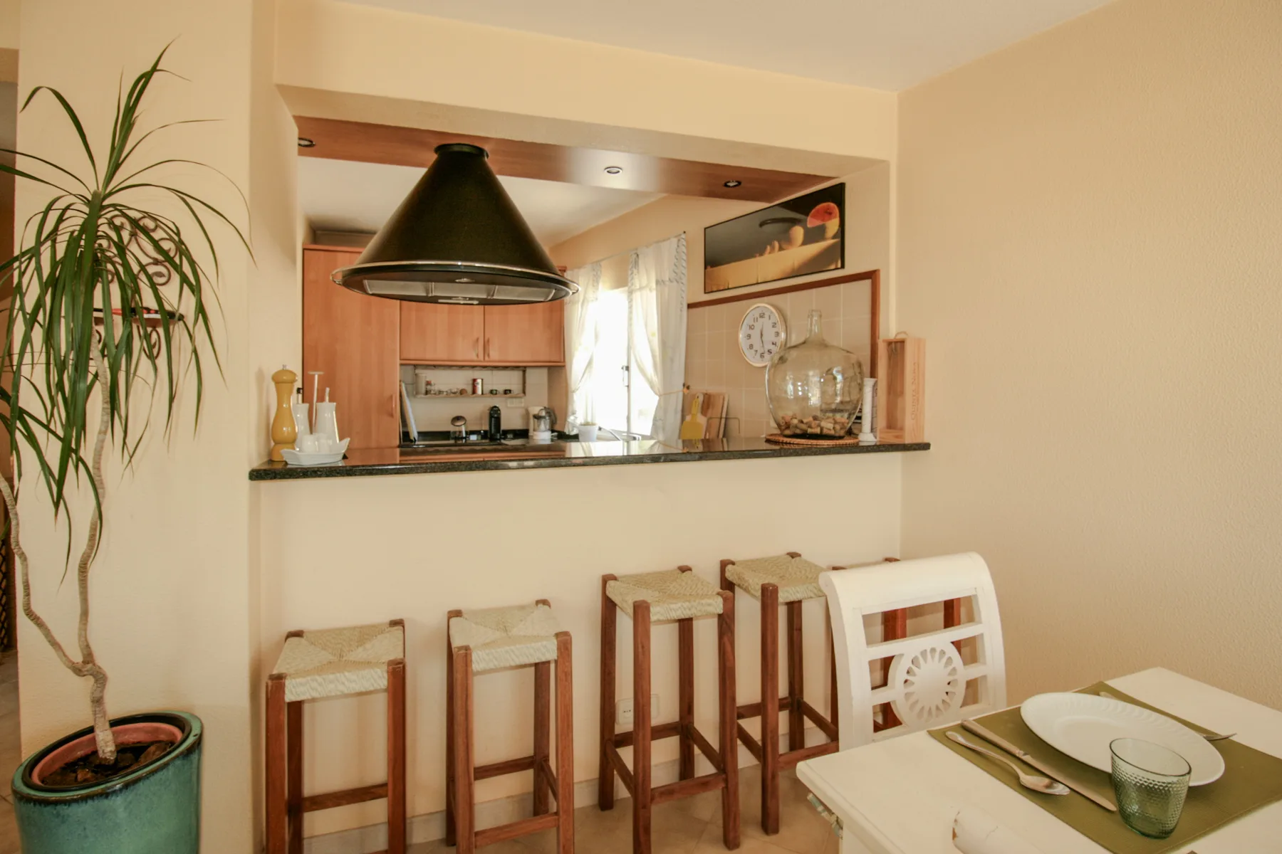 Una barra de cocina con asientos de madera y una mesa de comedor en primer plano.