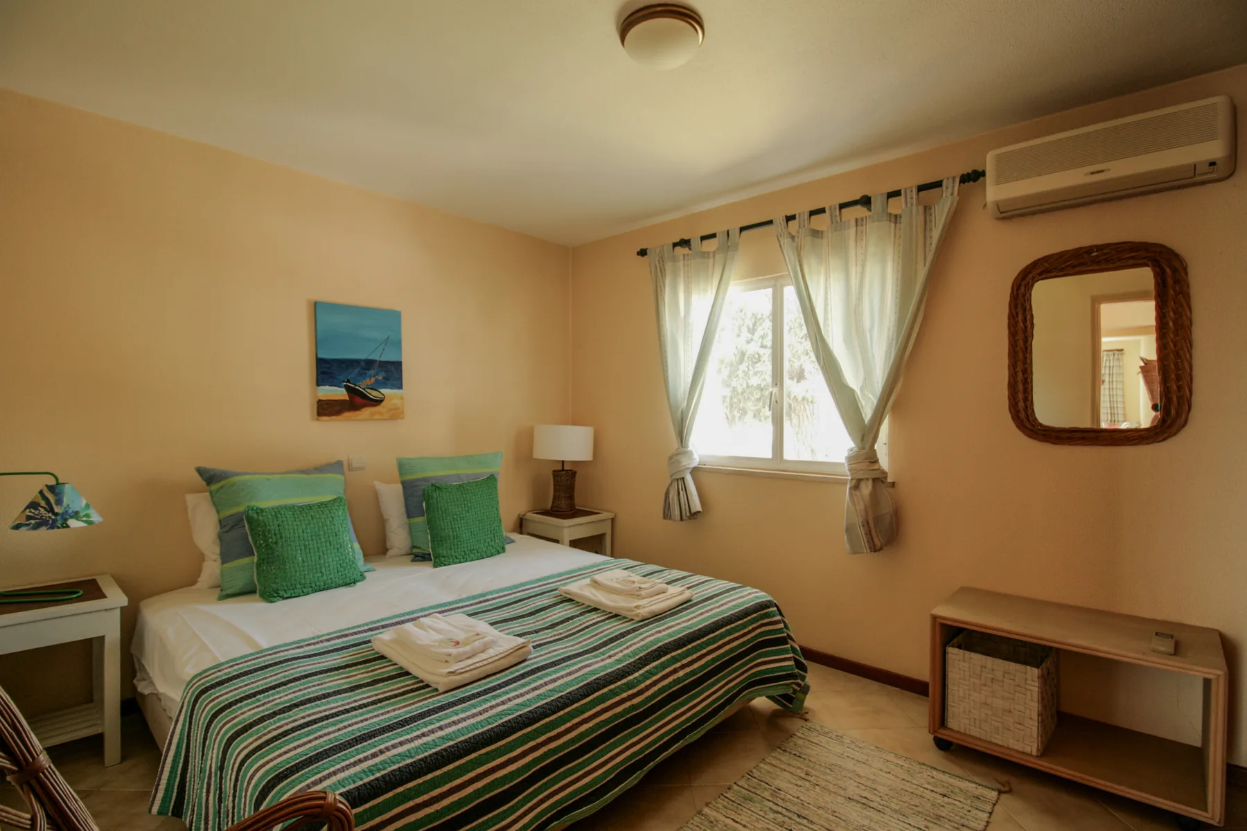 Dormitorio con cama doble, ropa de cama a rayas y una ventana con cortinas.