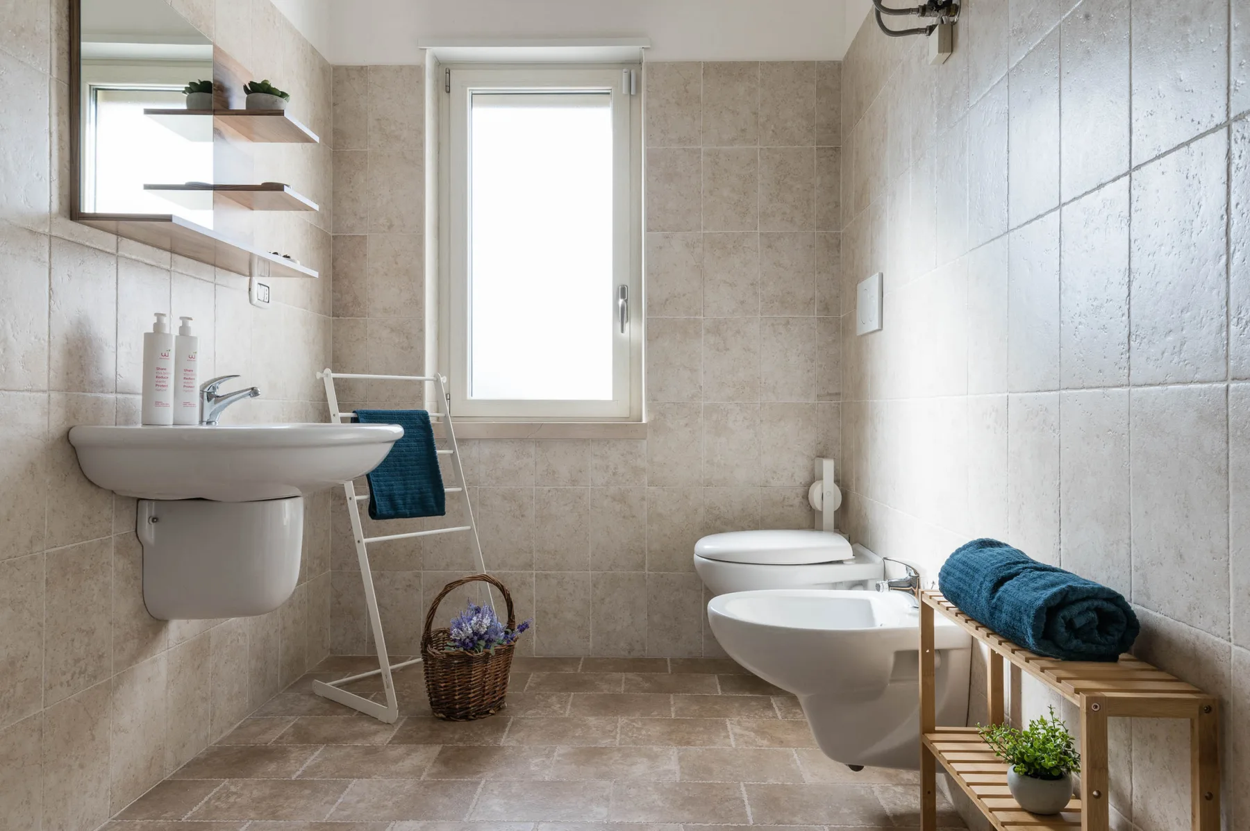Un baño alicatado con lavabo, inodoro y ventana.