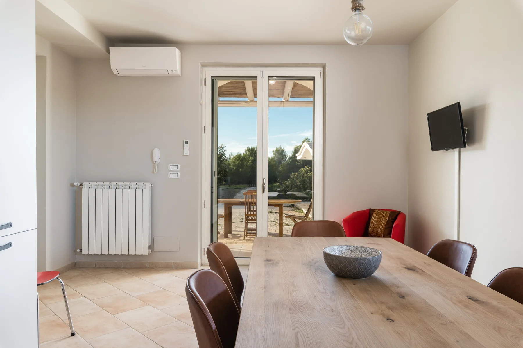 Comedor con una mesa de madera junto a puertas de vidrio que dan a un balcón.