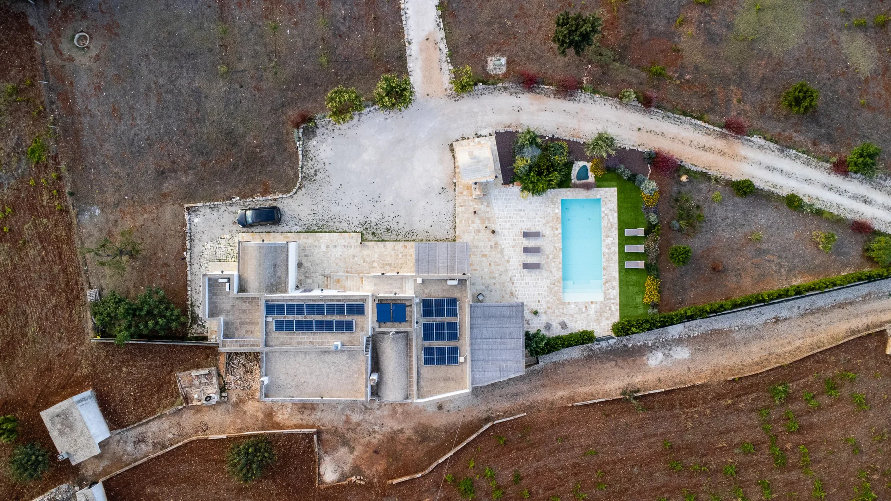 Vista aérea de una casa y una piscina junto a un camino curvo.