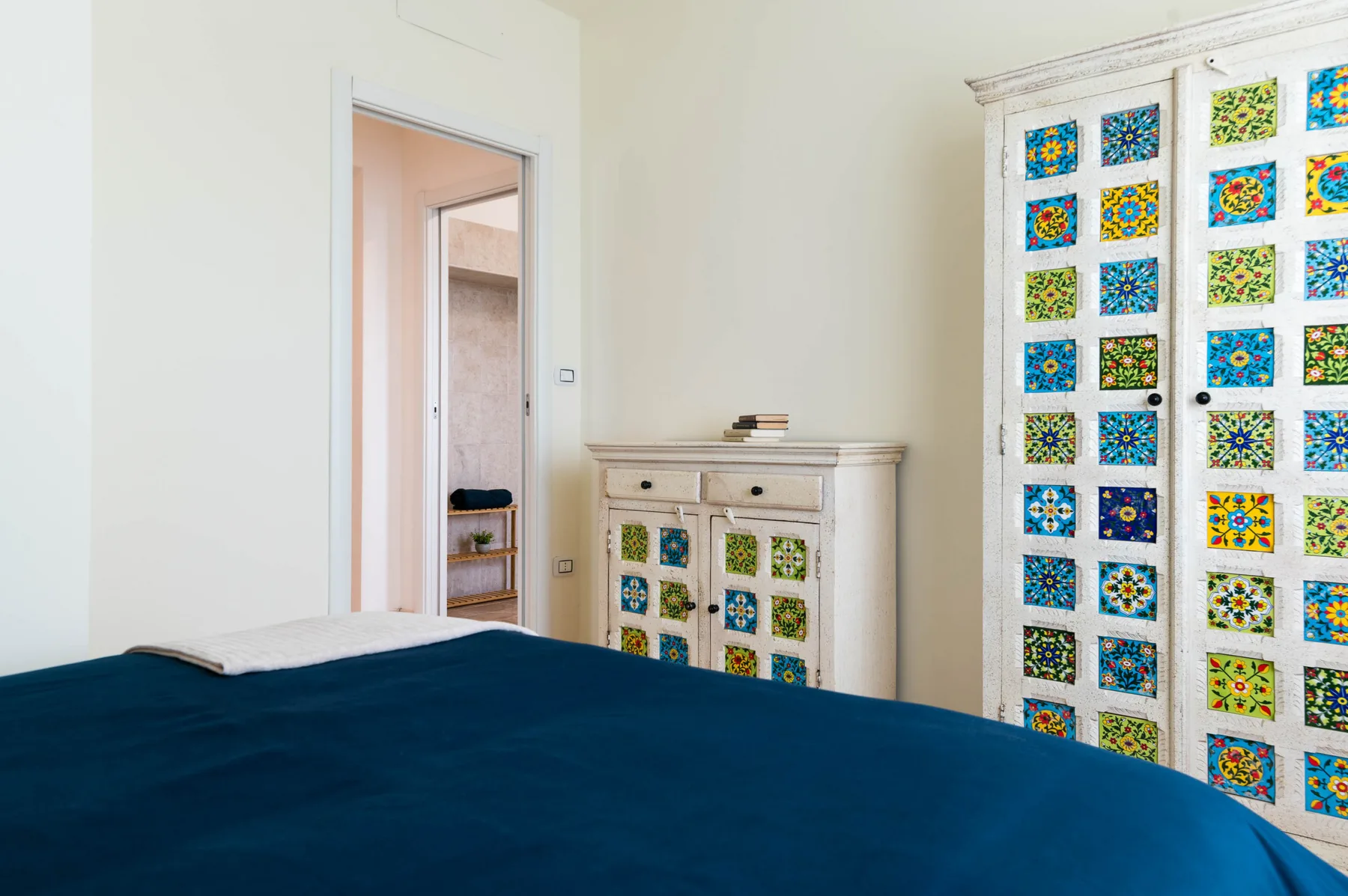 Un dormitorio con una cama y puertas de armario con motivos coloridos.