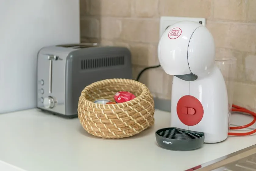 A kitchen counter displays a coffee machine, toaster, and small woven basket.