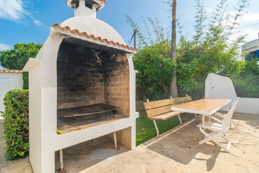 An outdoor patio with a built-in barbecue and a wooden table with seating.