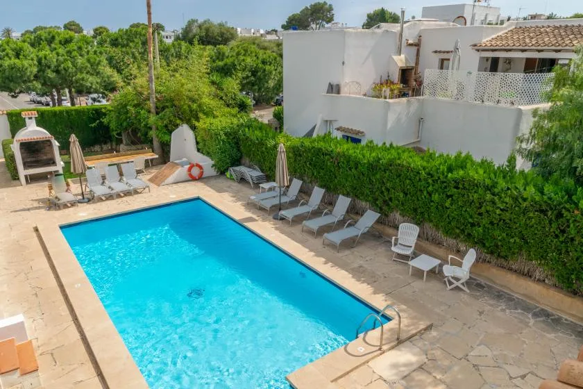 An outdoor swimming pool is surrounded by lounge seating and greenery.