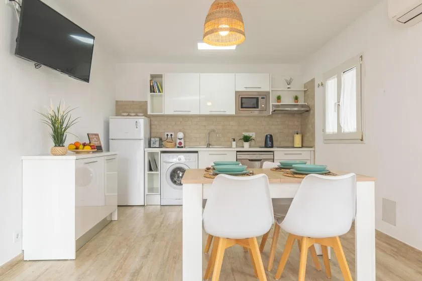 A bright kitchen and dining area with a white table and teal place settings.