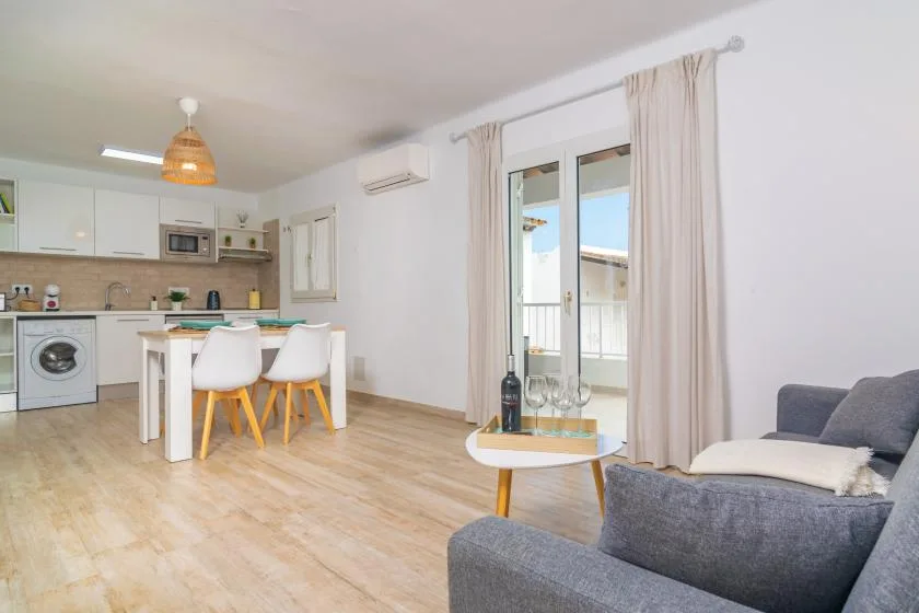 A bright open-plan living area with a dining table and kitchen.