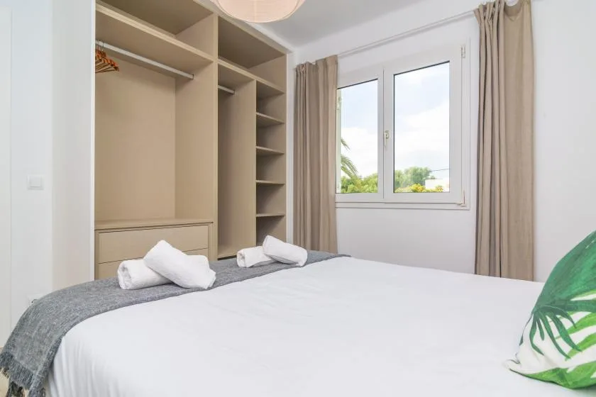 A bedroom with a bed, built-in shelving, and a window with curtains.