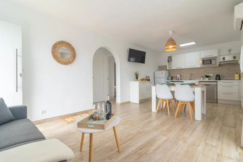 A bright open-plan living room and kitchen with a dining table and seating.