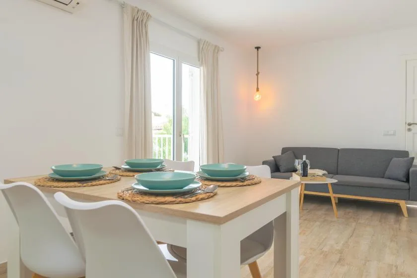 A bright dining and living area with a set dining table and gray seating.