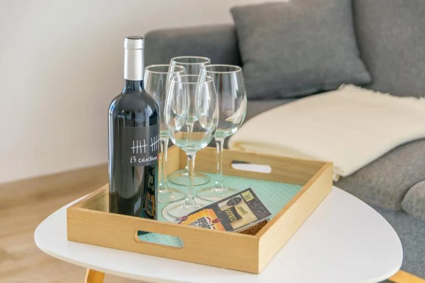 A drink tray with wine glasses sits on a white table beside gray seating.