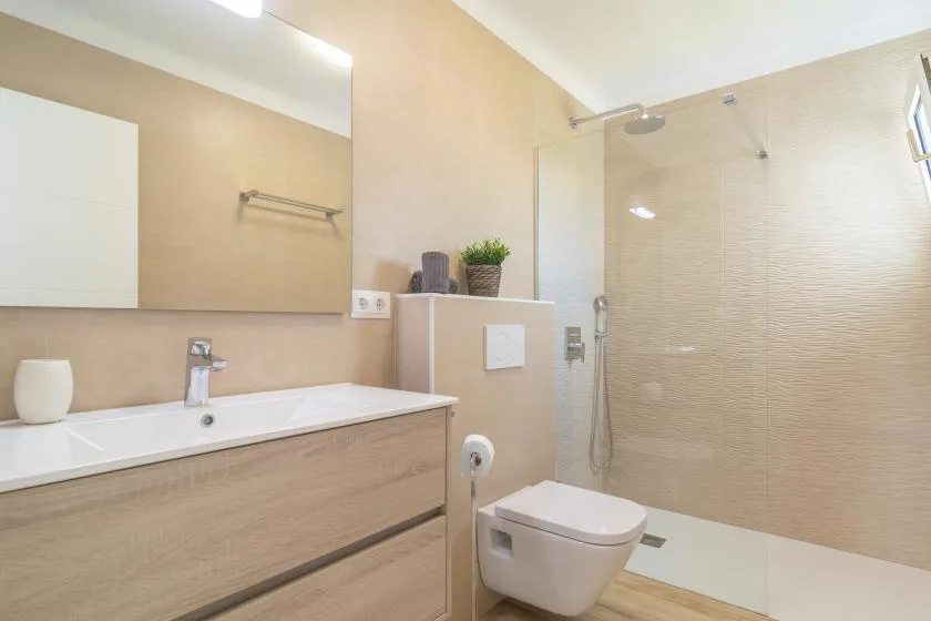 A bright bathroom with a sink, toilet, and walk-in shower.