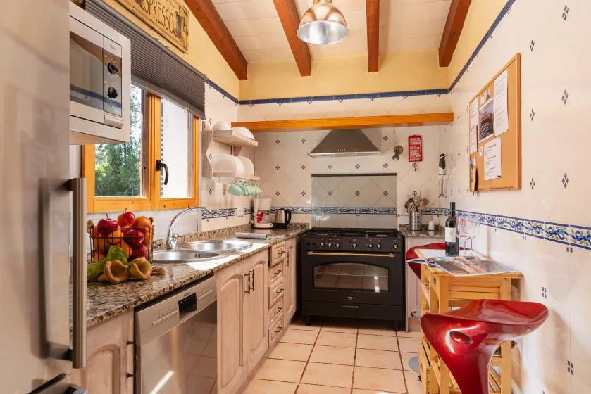 A bright kitchen with tiled walls, wooden cabinets, and a black stove.