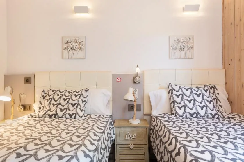 A bedroom with two beds, patterned bedding, and a small nightstand between them.