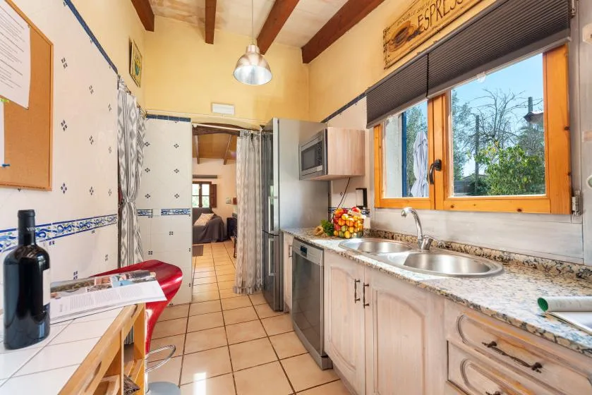 A tiled kitchen with a double sink beneath a large window.
