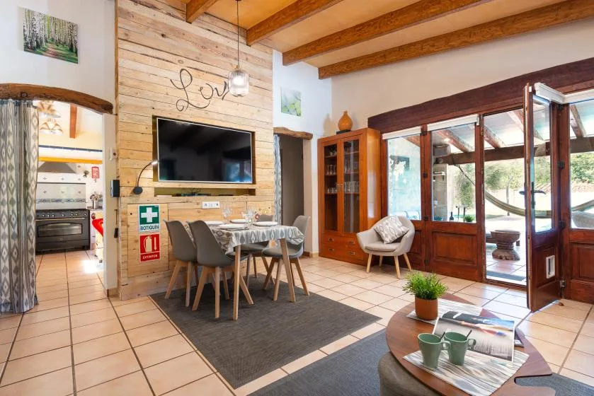 A dining and living area with a table, seating, and large windows.