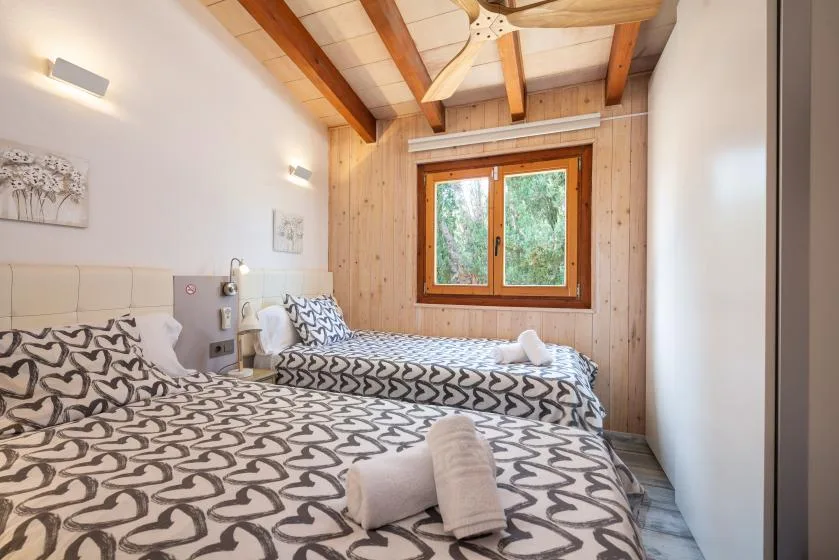 A bedroom with patterned bedding and a wooden-framed window.