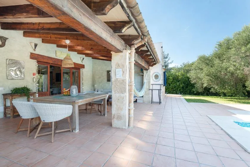 A covered outdoor dining patio opens onto a tiled terrace beside the pool.