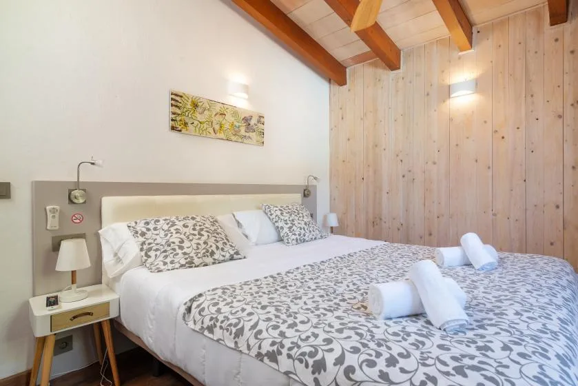 A bedroom with a large bed dressed in patterned bedding and towels.