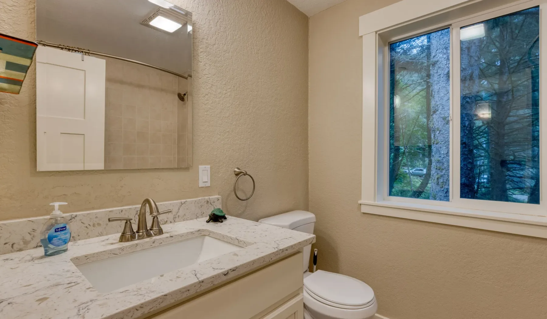 Un baño con lavabo, inodoro y una ventana grande.
