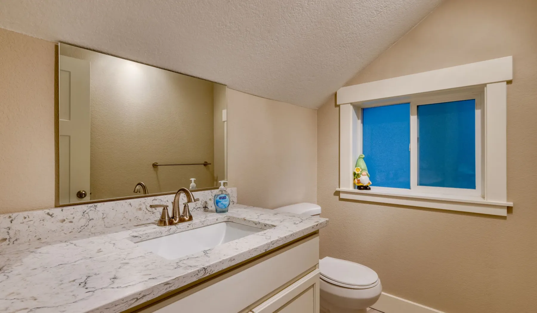 Un lavabo de baño está junto a una ventana, sobre un inodoro.