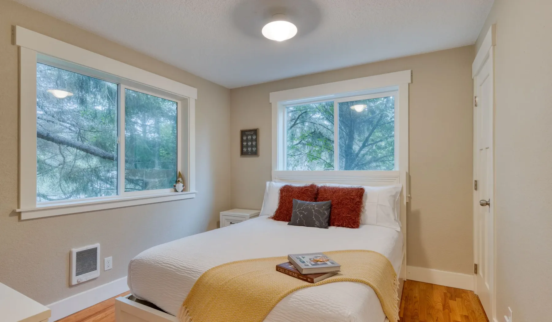 Un dormitorio con una cama bajo una ventana y otras ventanas en la pared lateral.