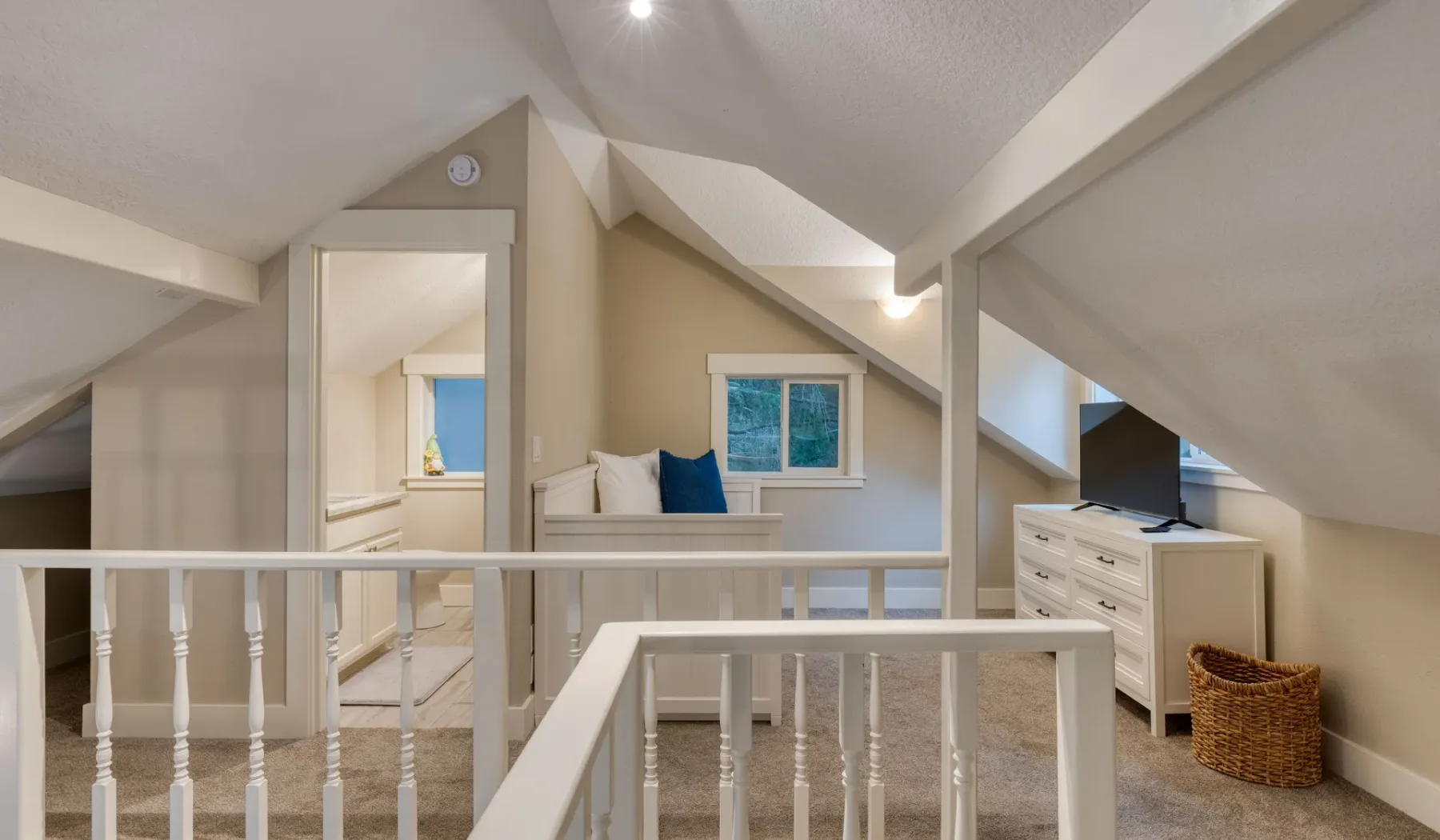 Un dormitorio en el ático con una cama, una ventana pequeña y techo inclinado.