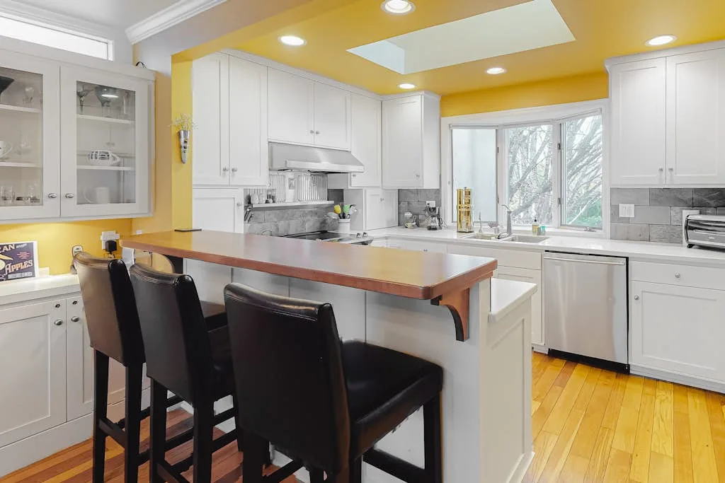 A bright kitchen with a large island and dark seating.