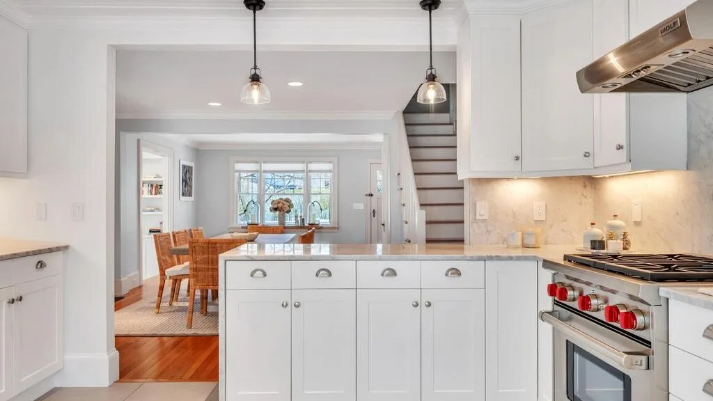 A bright kitchen with a central island and a dining area beyond.