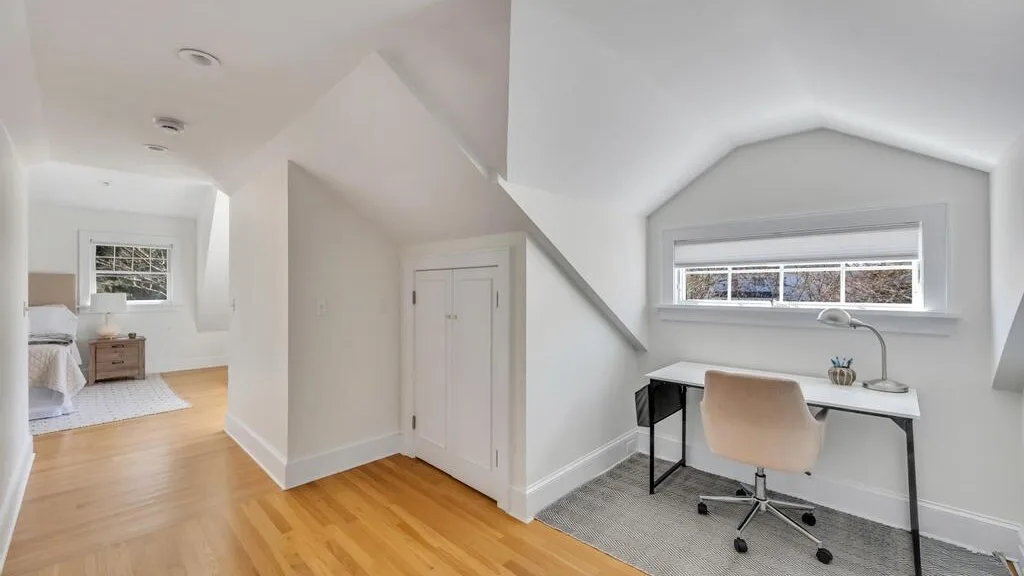 A bright attic workspace with a desk, chair, and sloped ceiling.