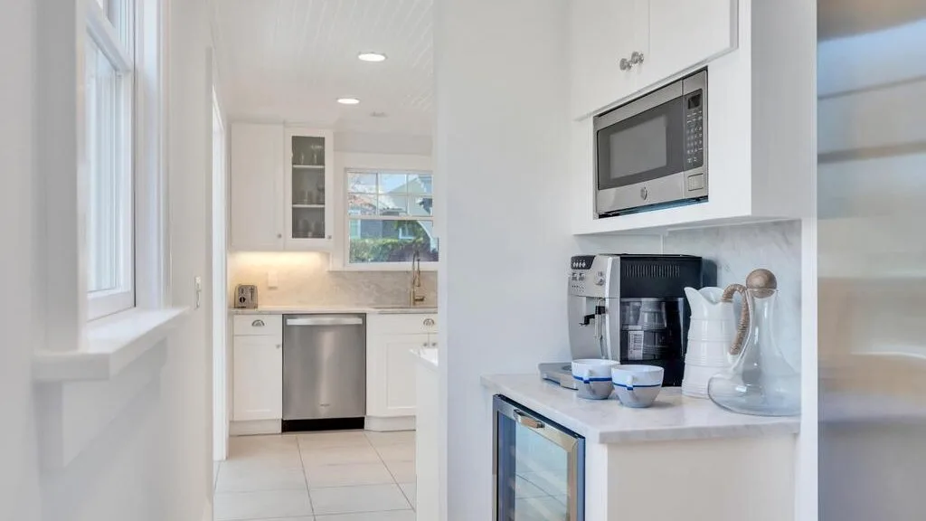A bright kitchen with white cabinets, a microwave, and a coffee maker.