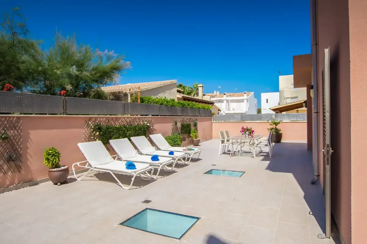 A sunny rooftop terrace with lounge seating, potted plants, and inset skylights.