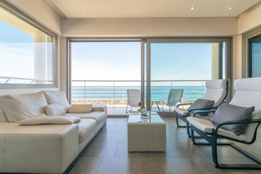A bright living room opens onto a balcony with ocean views.