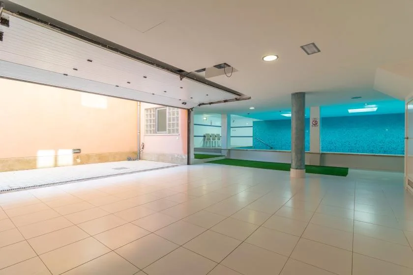 An indoor swimming pool area with tiled flooring and a turquoise pool.