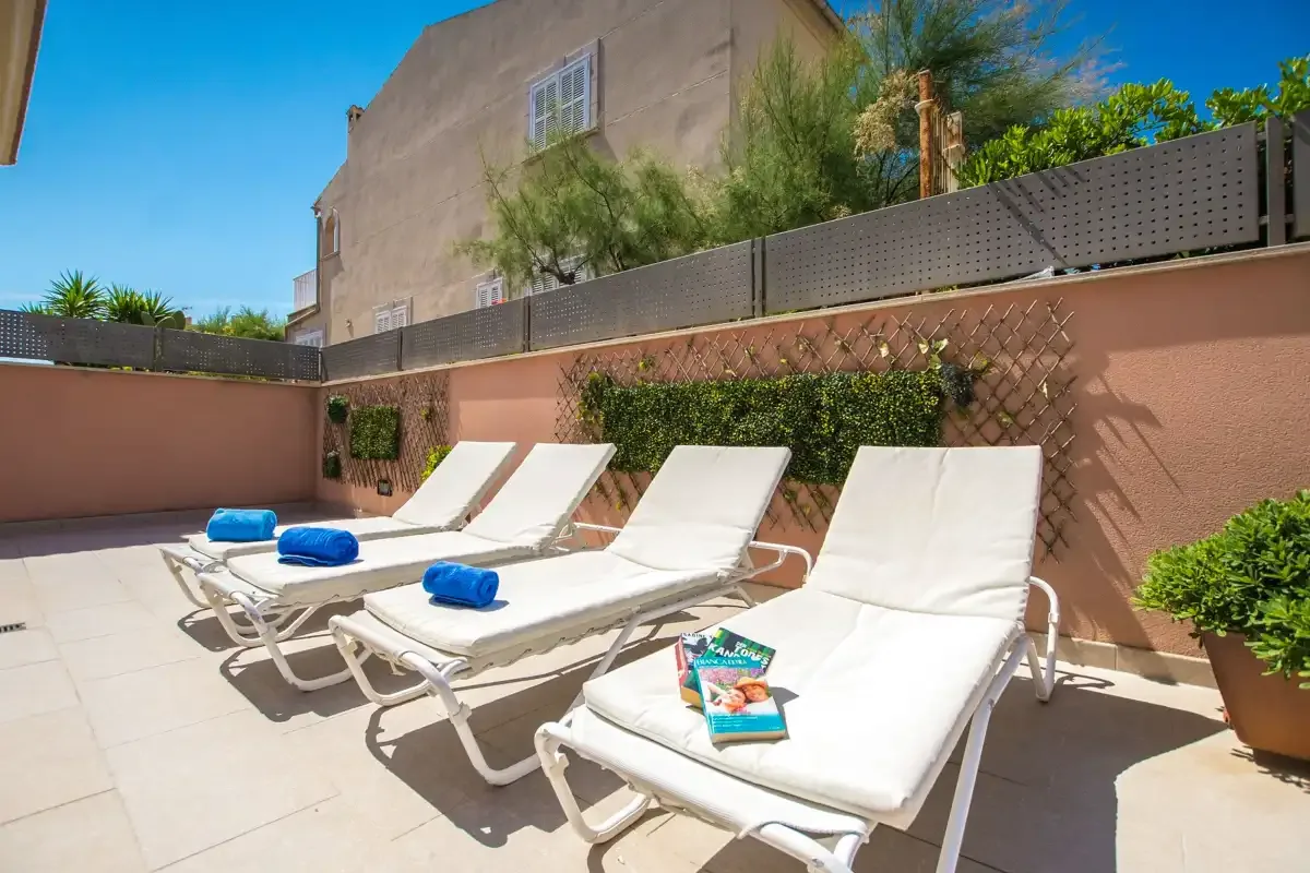 A sunny outdoor patio with reclining lounge chairs and blue towels.