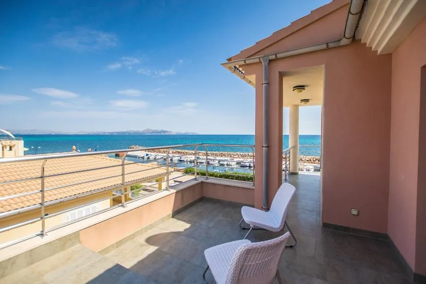 A seaside terrace with metal railings and views of the blue water.