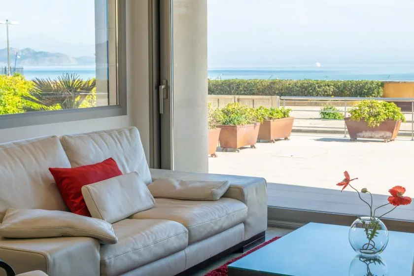 A bright living room opens onto a terrace overlooking the sea.