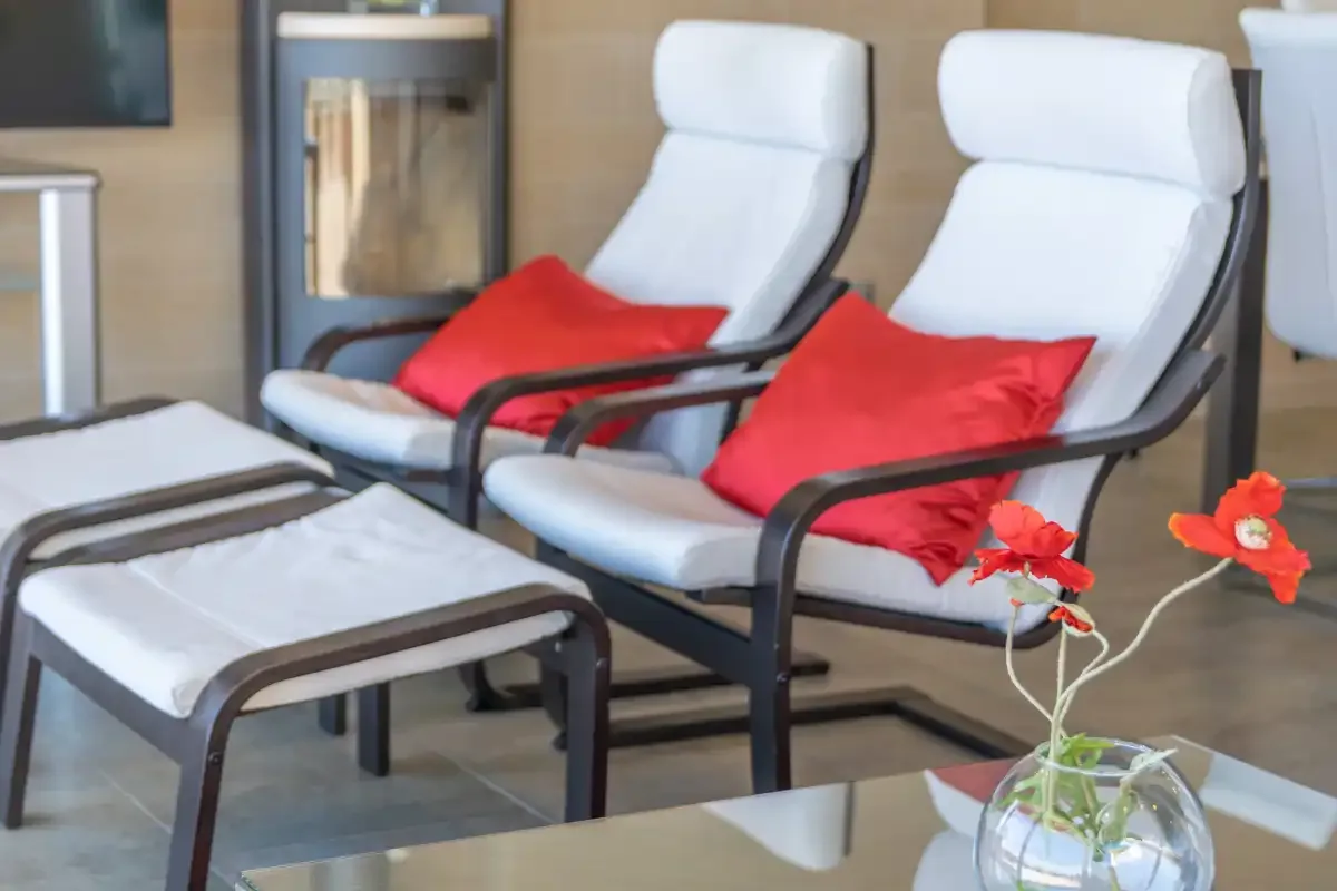 A lounge area with two reclining seats, red cushions, and a glass table.