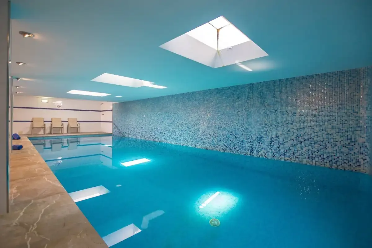 An indoor swimming pool with tiled walls and overhead skylights.