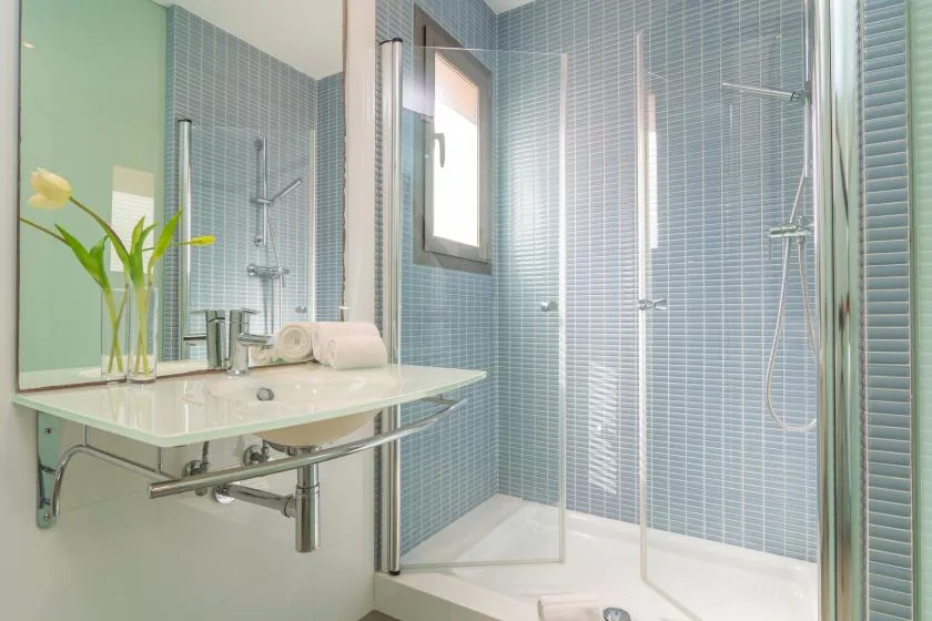 A tiled bathroom with a glass shower and a wall-mounted sink.